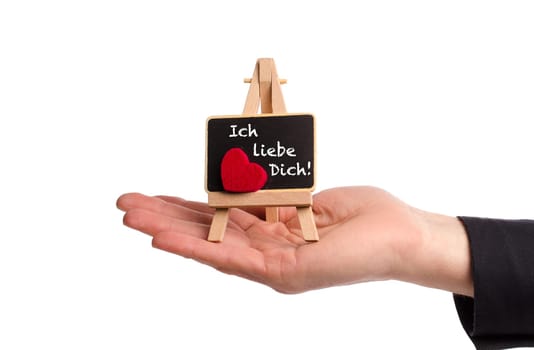 Hand hält Staffelei mit einer kleinen Tafel, Ich liebe Dich! als Valentinsgruß