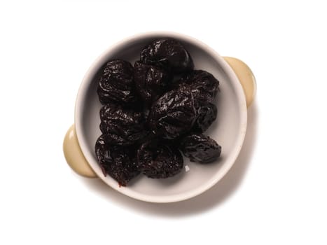 Dried plums in a bowl on a white background