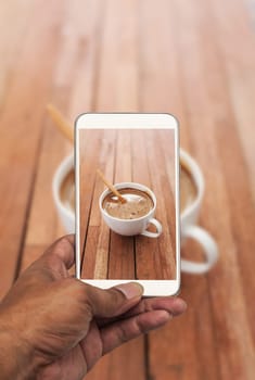 Image of shooting photograph with smartphone on cup of coffee