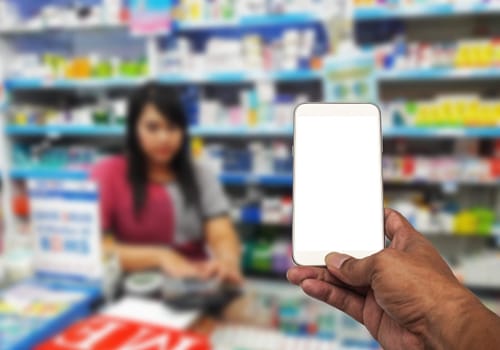Hand with smartphone white screen on blurred in pharmacy background