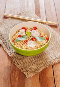 Noodle in bowl with chopsticks on wooden background