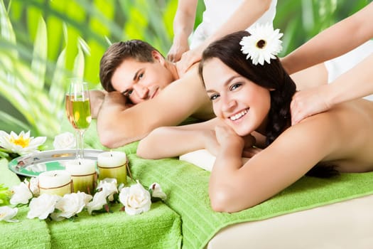 Portrait of smiling young couple receiving shoulder massage at beauty spa