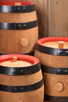 three old beer barrels with wooden plugs on a wooden background