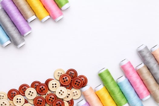 spool of threads and buttons on white background