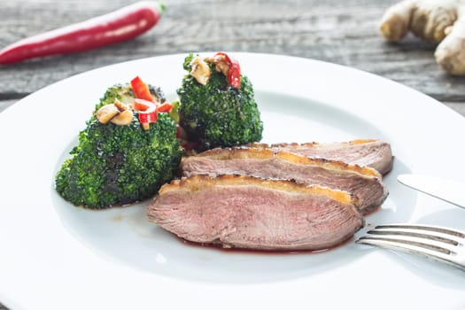 Duck breast with broccoli,chilli and cashew nuts on a plate