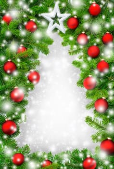 A frame of fir branches,Christmas baubles and snow forms the outline of a Christmas tree