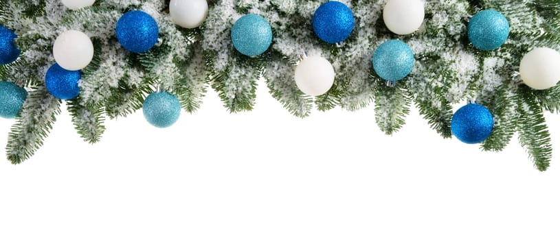 Decoration of snowy fir branches with Christmas balls on a white background
