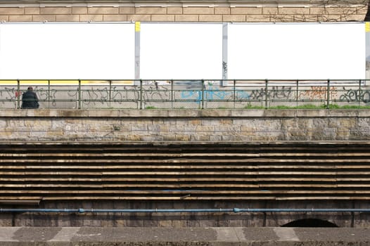 The wall of the Vienna underground network on which a man sits in front of empty billboards.