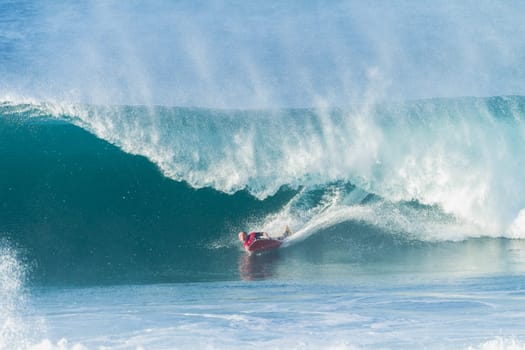 Surfing body-boarder rides large ocean wave
