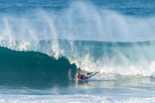 Surfing body-boarder rides large ocean wave