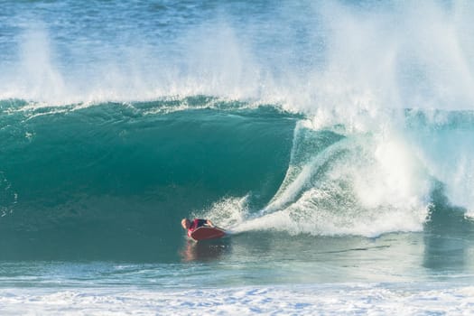 Surfing body-boarder rides large ocean wave