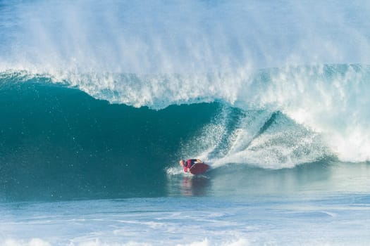 Surfing body-boarder rides large ocean wave