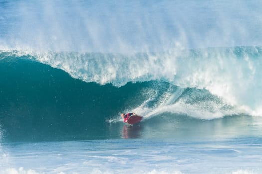 Surfing body-boarder rides large ocean wave
