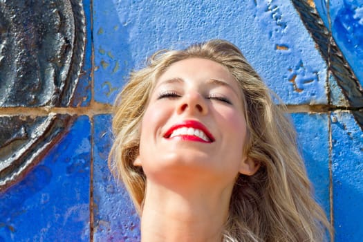 Young blonde woman in front of a blue wall
