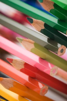 Close-up in oblique view over cross stacked crayons in the colors of the color circle with selective sharpness