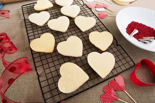 Heart shaped sugar cookies on cooling rake ready for decoration.