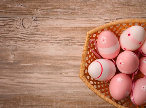 Pink Easter eggs in a basket on a wooden table