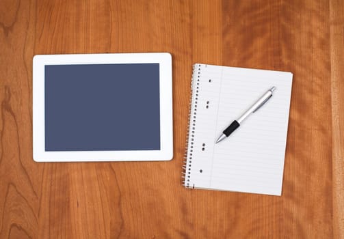 tablet PC and notepad with pen on wooden table from above
