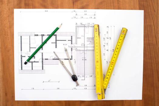 building plan with pencil, folding yardstick and compass on wooden table