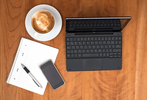 notebook,smartphone, notepad with pen and cappuccino on wooden table from above