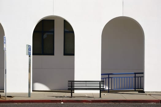 A park bench stands in front of a passageway with round arches.