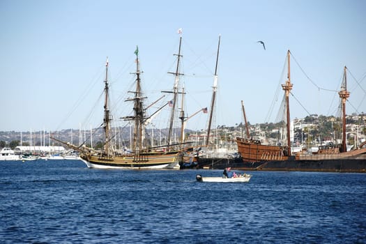 San Diego,United States - December 25,2015: A motorboat sails past the ancient and historic sailing ships of the San Diego Maritime Museum at the Port of San Diego on December 25,2015.