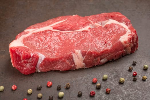 Raw dry aged rib eye steak with peppercorns
