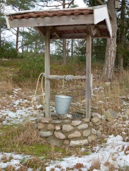 one old well in the forrest with a chain and a water range