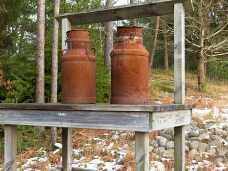 two old rusty milk jug on a bench like a beutiful ornament