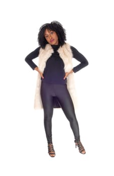 A lovely young African American woman in black tights and a white.fur coat with her hands on her hips, isolated for white background..