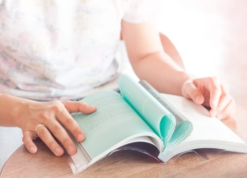 Woman reading book in coffee shop, stock photo