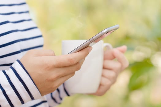 closeup female using phone and coffee drink in morning modern lifestyle
