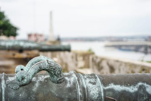 detail of old antique cannons overlooking the blurring city of havana, cuba
