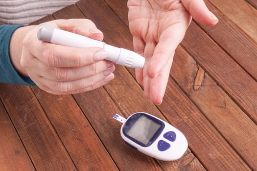 a lady&#39 s hands measuring blood glucose with a home test to control her diabetes