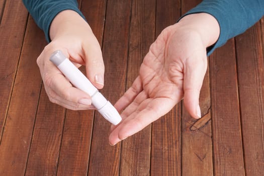 a lady&#39 s hands measuring blood glucose with a home test to control her diabetes