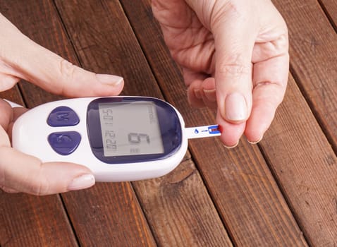 a lady&#39 s hands measuring blood glucose with a home test to control her diabetes