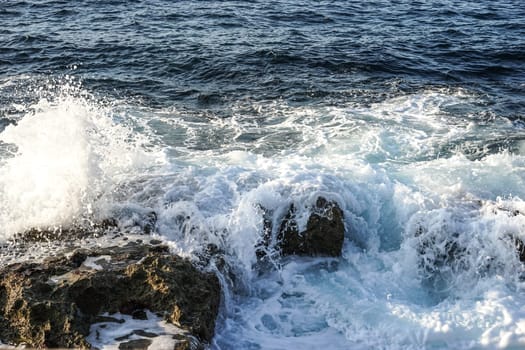 sea spray washes over the smooth stones on the beach. The waves breaking on a stony beach