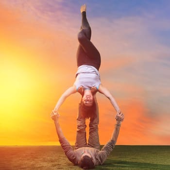 The two people doing yoga exercises against sunset sky
