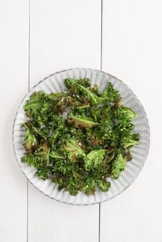 Kale chips with sea salt on a white plate