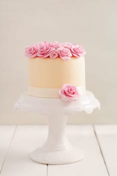 Ivory fondant covered cake with pink sugar roses on cake stand