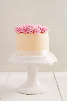 Ivory fondant covered cake with pink sugar roses on cake stand