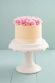 Ivory fondant covered cake with pink sugar roses on cake stand