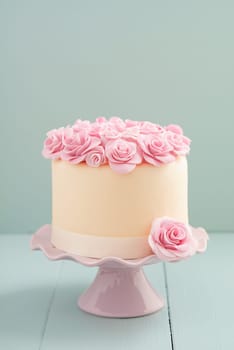 Ivory fondant covered cake with pink sugar roses on cake stand