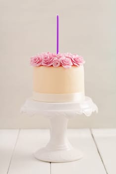 Ivory fondant covered cake with pink sugar roses on cake stand