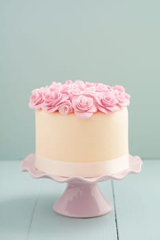 Ivory fondant covered cake with pink sugar roses on cake stand