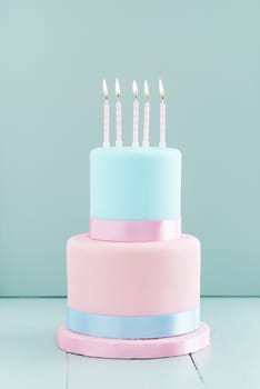 Fondant covered pastels coloured birthday cake with five birthday candles