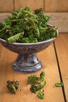 Kale chips with sea salt in a small dark serving bowl