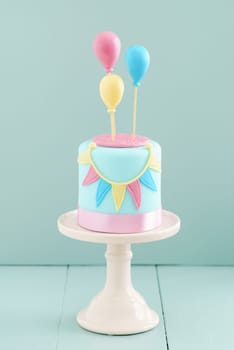 Fondant covered pastels coloured birthday cake with buntings and balloons