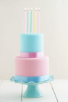Fondant covered pastels coloured birthday cake with four birthday candles