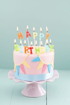 Fondant covered pastels coloured birthday cake with happy birthday candles